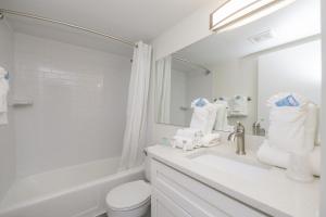 a white bathroom with a sink and a toilet at Siesta Key Beach Resort and Suites in Sarasota