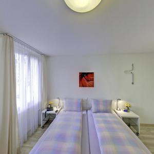 a large bed in a white room with two tables at Hotel Sporting in St. Gallen
