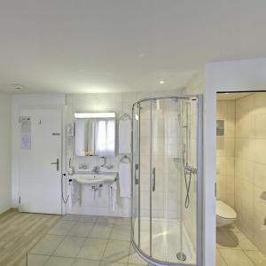 La salle de bains est pourvue d'une douche et d'un lavabo. dans l'établissement Hotel Sporting, à Saint-Gall
