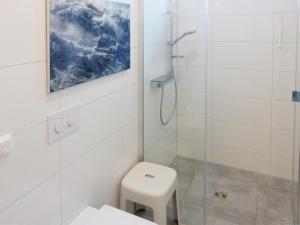 a white bathroom with a shower and a toilet at Weiße Düne Ferienwohnung *Weiße Düne 7* in Wittdün +26 photos