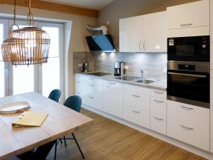 a kitchen with white cabinets and a wooden table at Weiße Düne Ferienwohnung *Weiße Düne 7* in Wittdün