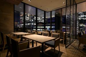 a restaurant with tables and chairs and a city skyline at remm Tokyo Kyobashi in Tokyo