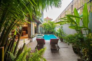 a deck with chairs and a swimming pool in a house at Villa Suzuki 1 Seminyak in Seminyak