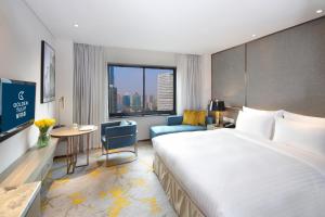 a hotel room with a large bed and a desk at Golden Tulip Shanghai Hongqiao - A Louvre Hotel in Shanghai