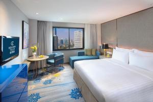 a hotel room with a large bed and a desk at Golden Tulip Shanghai Hongqiao - A Louvre Hotel in Shanghai