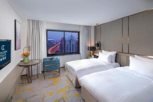 ein Hotelzimmer mit 2 Betten und einem Fenster in der Unterkunft Golden Tulip Shanghai Hongqiao - A Louvre Hotel in Shanghai