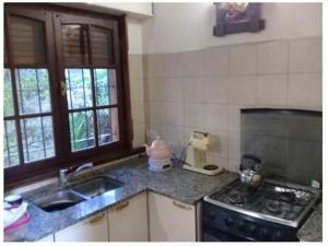 a kitchen with a sink and a stove at Cabaña Paso a Paso in Tandil