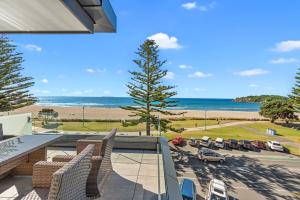 a balcony with chairs and a view of the beach at Pavilion Beachfront Apartments in Mount Maunganui