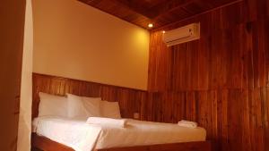 a bedroom with a bed with a wooden wall at Free Beach Resort in Phú Quốc