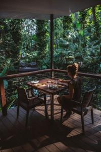 a woman sitting at a table on a deck at Daintree Ecolodge in Daintree