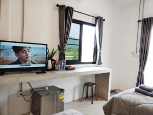 een woonkamer met een televisie op een tafel met een raam bij Santitham Home Farm Stay in Mae Taeng