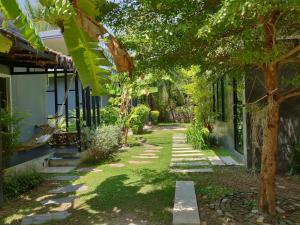 a garden with a walkway next to a house at Coco Coozy in Kanchanaburi