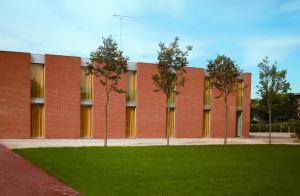 a red brick building with trees in front of it at La Corte Albergo Meublé in Bagnolo San Vito