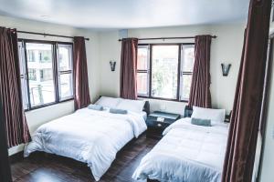 Dos camas en una habitación con dos ventanas. en Hotel K2 Pokhara, en Pokhara