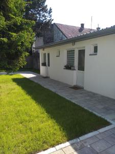une maison blanche avec une pelouse à côté dans l'établissement Rooms Jelena, à Zrenjanin