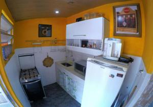 uma pequena cozinha com paredes amarelas e um frigorífico branco em Confortável Cobertura Copacabana no Rio de Janeiro