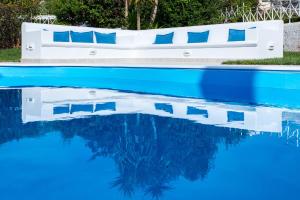 a pool with blue water and a bed with blue pillows at Sarwnisland in Lagonissi