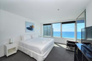 a white bedroom with a bed and a television at Deluxe Private Apartment in Surfers Paradise in Gold Coast