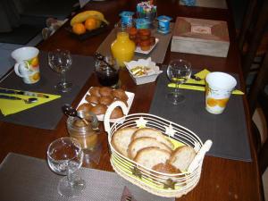 una mesa con una cesta de pan y copas de vino en LA GRANGE DU RIAL en Bournazel