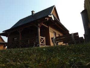 uma cabana de madeira com um alpendre e relva à sua frente em CHATA JASNA 2km od TATRALANDIE em Liptovský Trnovec