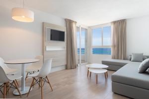 a living room with a couch and a table and chairs at Hotel Palia Sa Coma Playa in Sa Coma