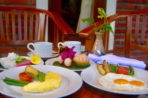 a table with plates of breakfast food on it at Dhiari Guest House in Ubud