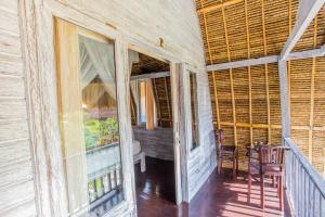 um alpendre de uma casa com cadeiras e uma mesa em Secret Point Huts em Nusa Lembongan