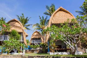 een groep huisjes op het strand met palmbomen bij Secret Point Huts in Nusa Lembongan