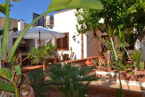 Un patio con mesa y sillas y plantas. en La Terrazza Di San Vito, en San Vito lo Capo
