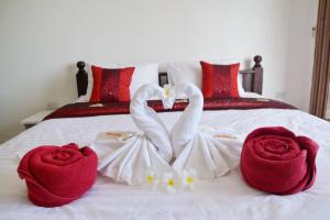 two swans dressed in white are sitting on a bed at White Flower Lanta in Ko Lanta
