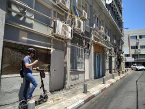 a man riding a scooter on a city street at AirTLV - Centrally Located Studio With Gallery in Tel Aviv