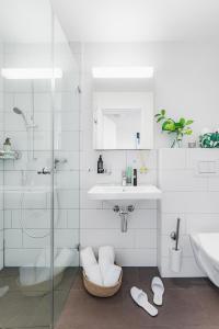 a white bathroom with a sink and a shower at Swiss Star Oerlikon Lodge - Self Check-In in Zürich