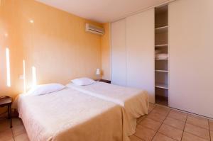 1 dormitorio con cama blanca y armario en Résidence Les Jardins de Massane, en Baillargues