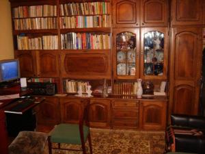 a library with wooden cabinets and a desk with a computer at Pensiunea Tarina in Şuncuiuş
