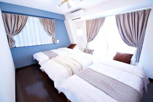 - 2 lits dans une chambre avec des murs bleus et une fenêtre dans l'établissement Kanbe Building 301, à Tokyo