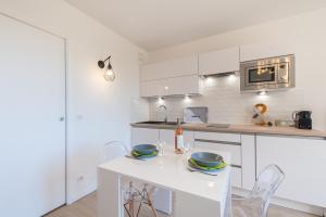 a white kitchen with a white table and chairs at Studio del Sol in Saint-Cyr-sur-Mer