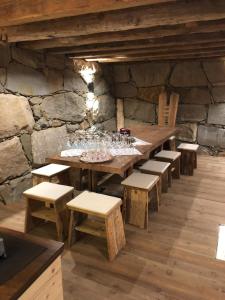 a room with a wooden table and benches and a stone wall at Hotel Pozzamanigoni in Selva di Val Gardena