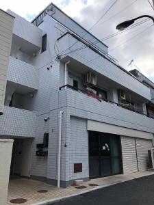 a white brick building with a parking lot at Kanbe Building 301 in Tokyo
