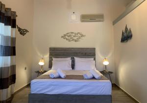 a bedroom with a bed with blue pillows and two lamps at Iliovasilema in Platy