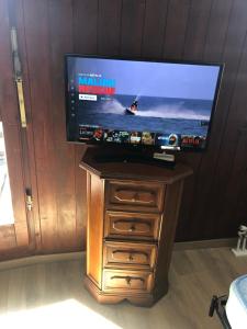 a flat screen tv on a wooden stand with a dresser at Monolocale Cielo Alto in Breuil-Cervinia