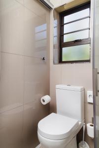 uma casa de banho com um WC e uma cabina de duche em vidro. em Loerie Guest Lodge em George