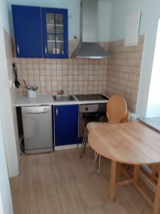 a small kitchen with blue cabinets and a wooden table at Apartments Lina in Karlobag