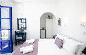 a white bedroom with a bed and a blue door at Villa Happening in Imerovigli