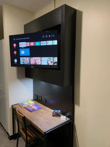 TV colgada en una pared con mesa de madera en The Stuart Hotel-Motel, en Katherine