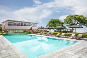 a pool with chairs and umbrellas in front of a building at Coral Sea Resort & Casino in Honiara