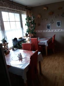 a dining room with two tables and red chairs at Pension Stürrad in Neuharlingersiel