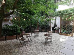 ローマにあるGuesthouse Coronari Courtyardのテーブルと椅子、木々と照明が備わるパティオ