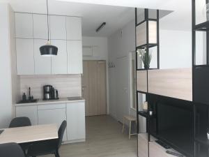 a kitchen with white cabinets and a table and a dining room at Apartamenty Świnoujście - Wyspiańskiego 34e in Świnoujście