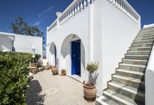 une maison blanche avec une porte bleue et des escaliers dans l'établissement Villa Happening, à Imerovigli