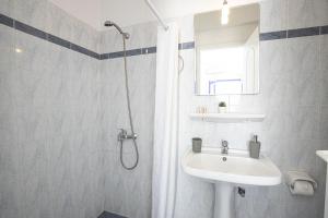 La salle de bains blanche est pourvue d'un lavabo et d'une douche. dans l'établissement Villa Happening, à Imerovigli